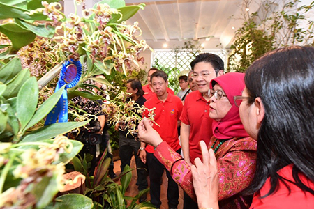 NParks CEO Mr Kenneth Er and Minister Lawrence Wong look on as President Halimah Yacob admires one of the award-winning entries at the SGF Orchid Show 2018.